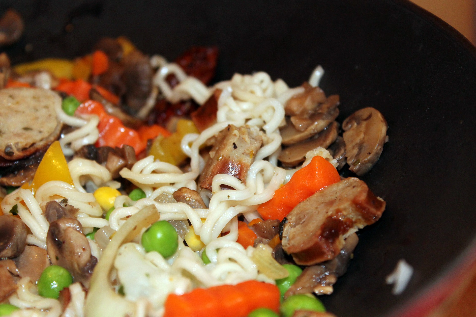cocina con wok de pollo con verduras, encimera con control de llama